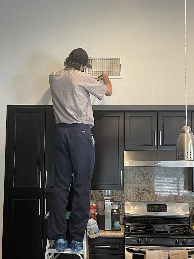 Technician inspecting an air vent during HVAC service in Sharonville